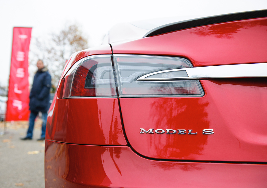 PARIS FRANCE - NOVEMBER 29, 2014: Tesla Model S signage of a red car outside the dealership house with male silhouette admiring the car. Tesla is an American company that designs manufactures and sells electric cars