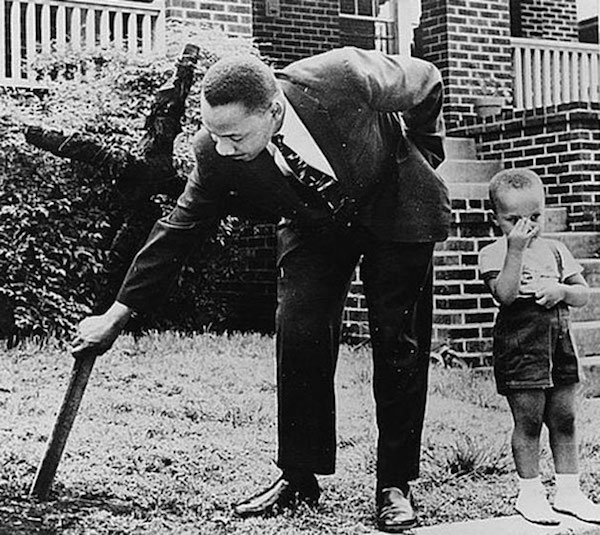 Martin Luther King Jr. junto a su hijo arranca una cruz quemada en el patio de su casa, 1960