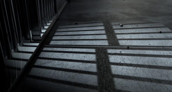 A closeup of view of a jail cells iron bars casting shadows on the prison floor with copy space ** Note: Visible grain at 100%, best at smaller sizes