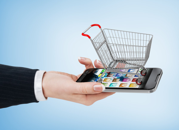 Woman hand holding smartphone with shopping cart. E-commerce concept.