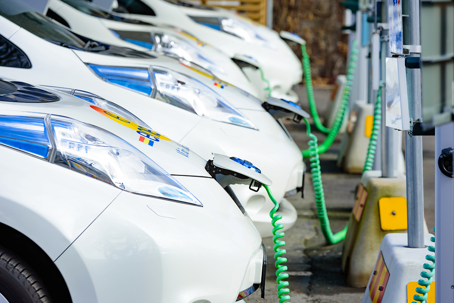 Kristianstad Sweden - March 20 2016: The charging of some white Nissan electrical cars. Green coiled cables are attached to the front of the cars. These are C4 Energi carpool rentals.
