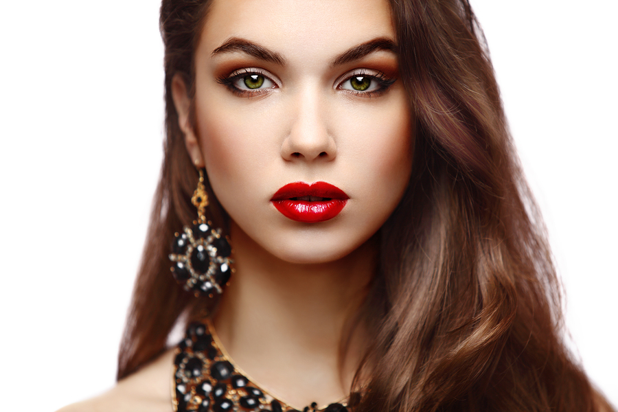 Beauty Model Woman with Long Brown Wavy Hair. Healthy Hair and Beautiful Professional Makeup. Red Lips and Smoky Eyes Make up. Gorgeous Glamour Lady Portrait. Haircare, Skincare concept